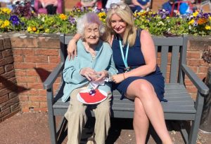 Care home manager Sandra McNay with resident Violet Wright. Sat on a bench smiling and hugging