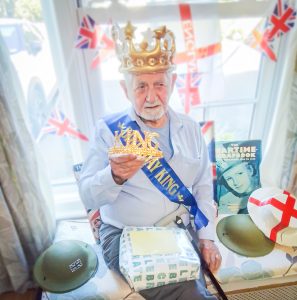 Birthday boy, Jerzy Snigorski wearing a novelty gold crown with a blue birthday sash and a present on his lap